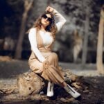 Fashionable woman with sunglasses posing in an autumn Indian forest.
